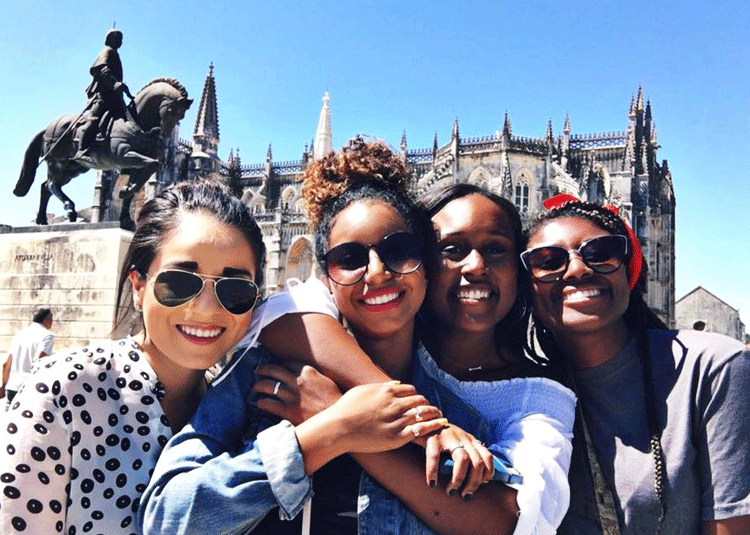 4 girls in front of historical building and horse and rider statue